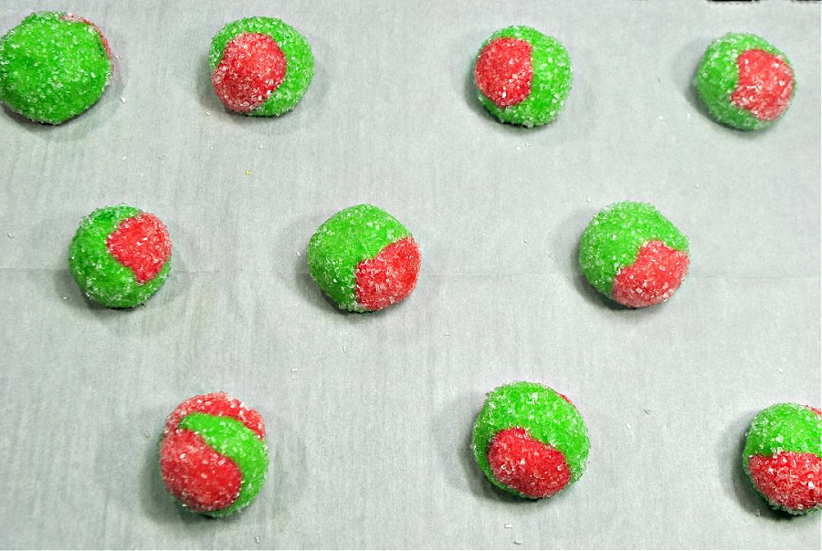 red and green dough balls on a parchment lined baking sheet