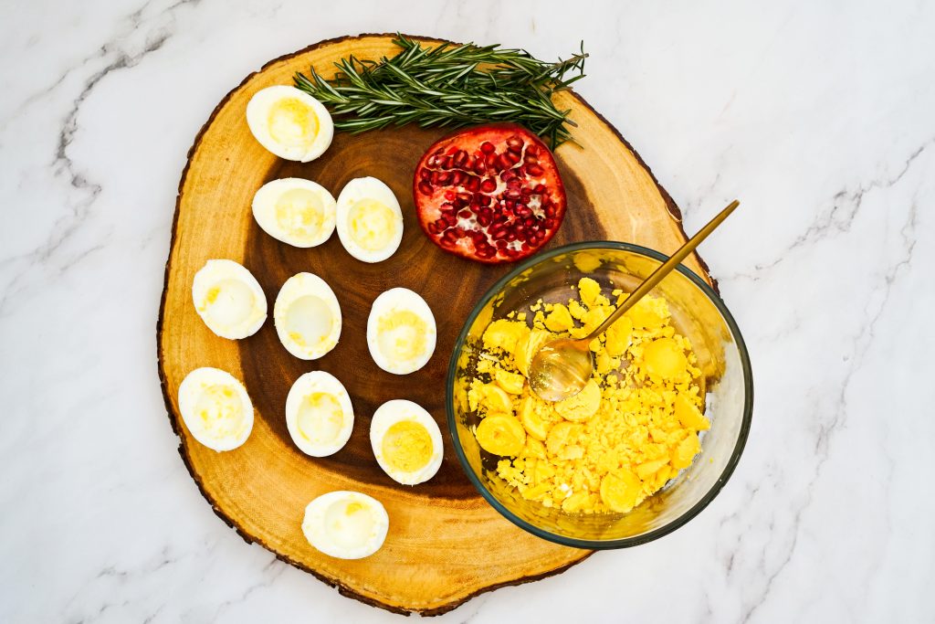 egg halves on a wooden cutting board with a small bowl of yolks