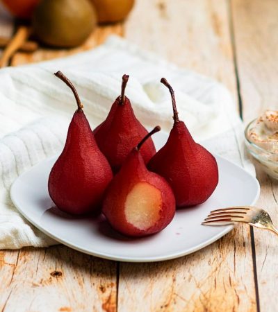 close up of red wine poached pears on a white plate