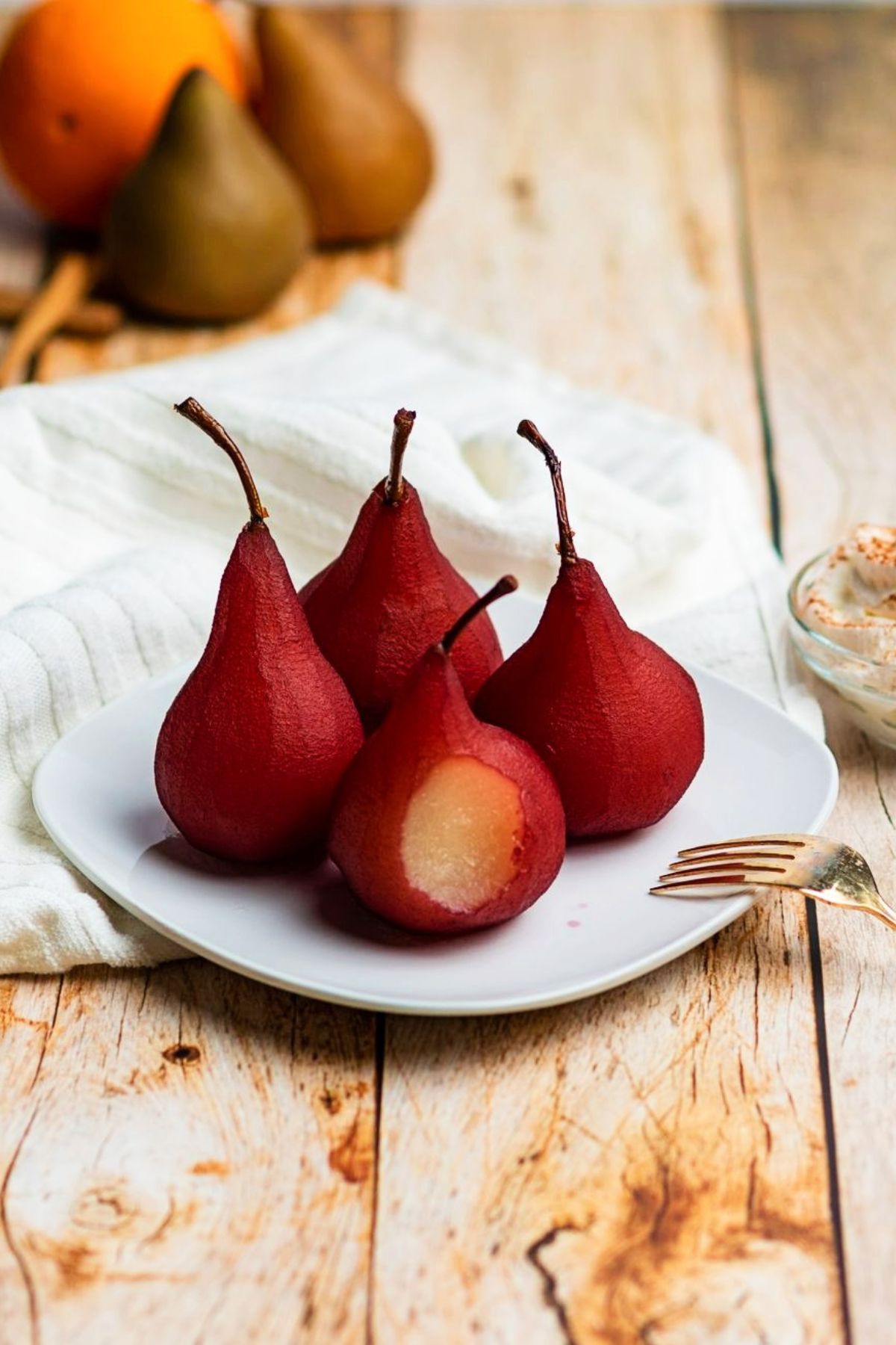 close up of red wine poached pears on a white plate 