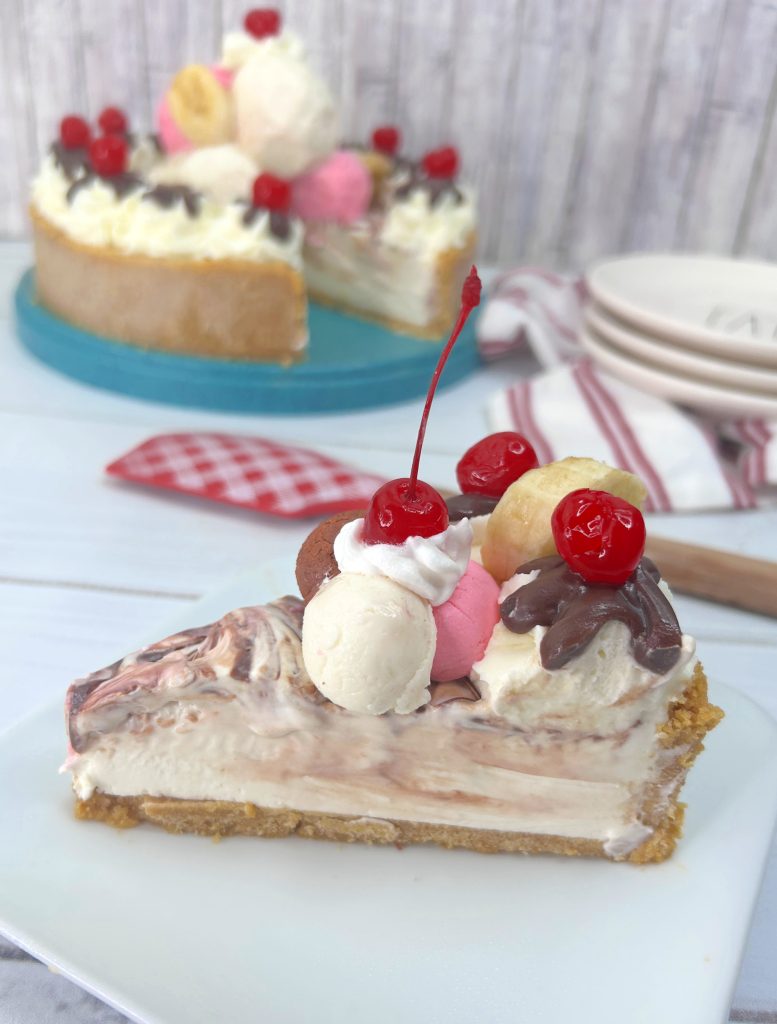 Slice of banana split no bake pie decorated with frosting and cherries
