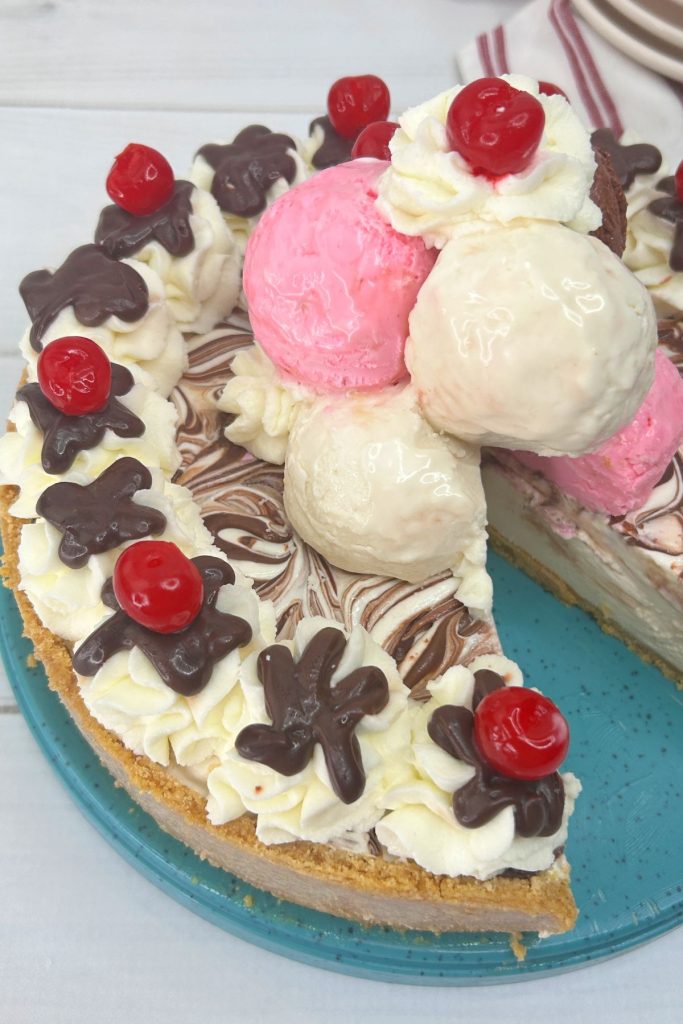 whole banana split cake on a blue plate with a slice missing.