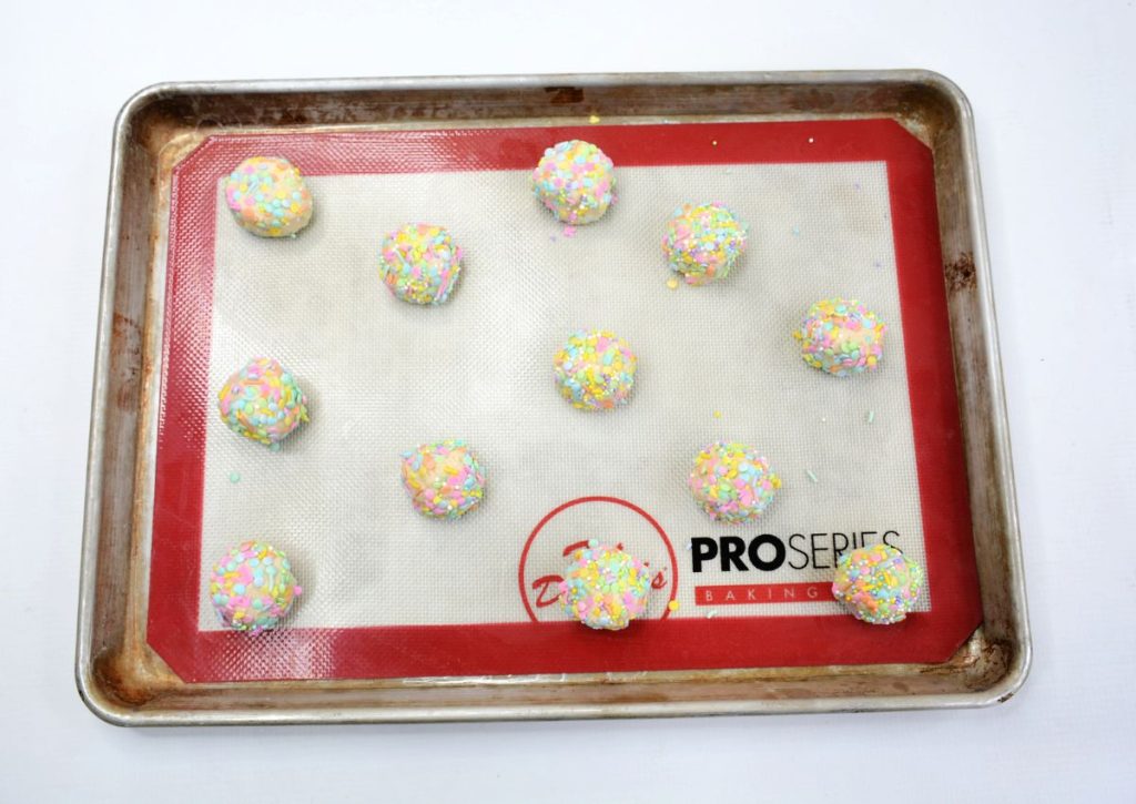 cookie dough balls on a silicone lined cookie sheet.
