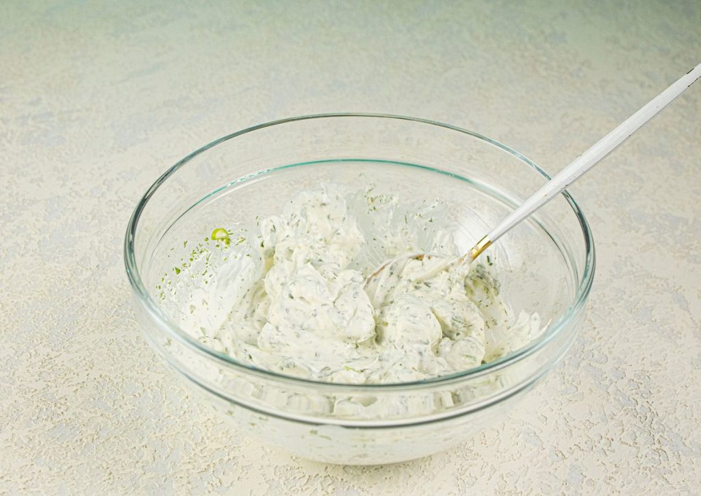 Cream cheese and seasonings being mixed in a bowl.