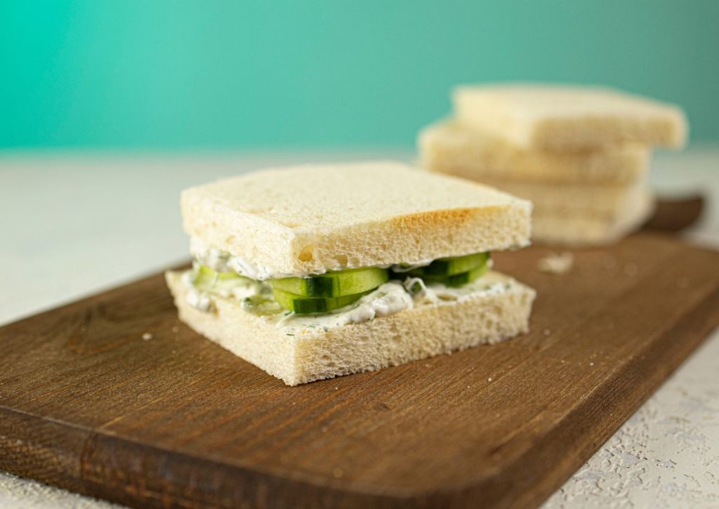 Sandwiches being stacked on a wooden cutting board.