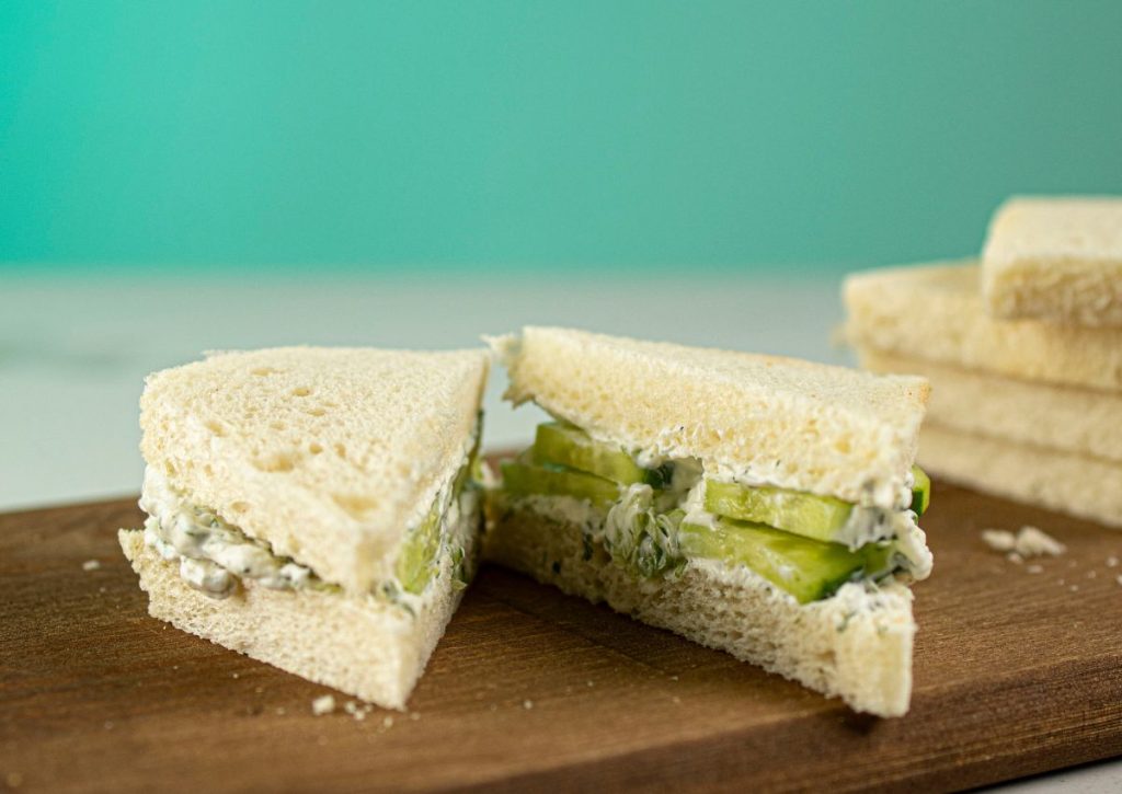 Sandwich being cut on a wooden cutting board.