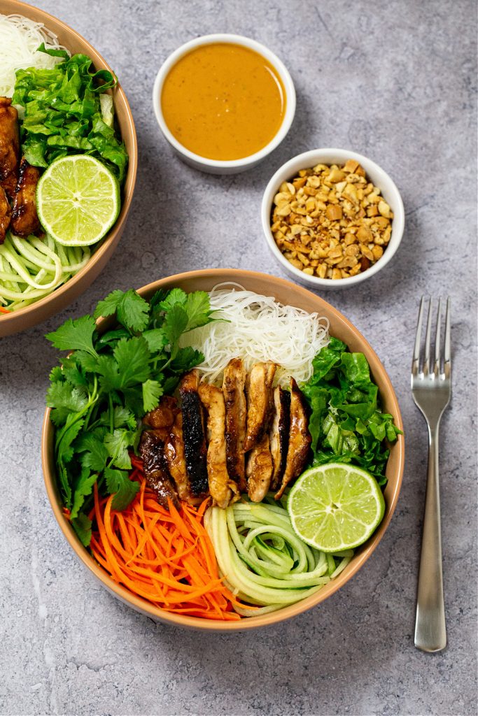 A bowlful of sliced chicken thighs and vegetables in a spicy peanut sauce.