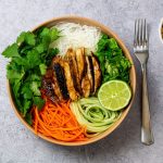 Wooden bowl full of peanut chicken bowl.