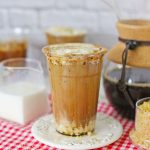 Plastic cup full of brown sugar shaken espresso on a white saucer.