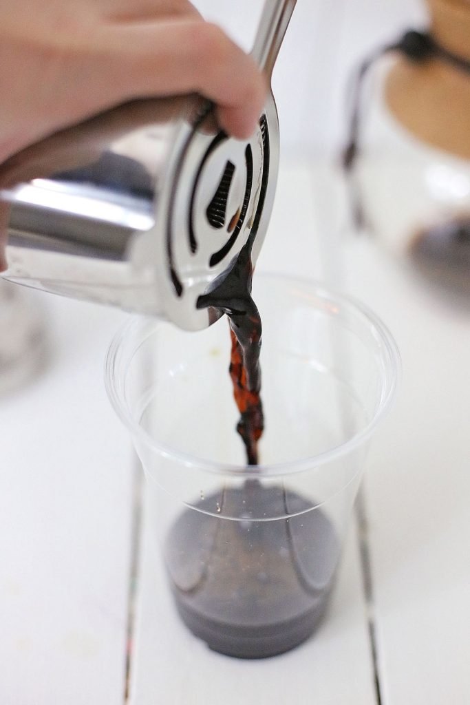 Espresso being poured into a plastic cup.