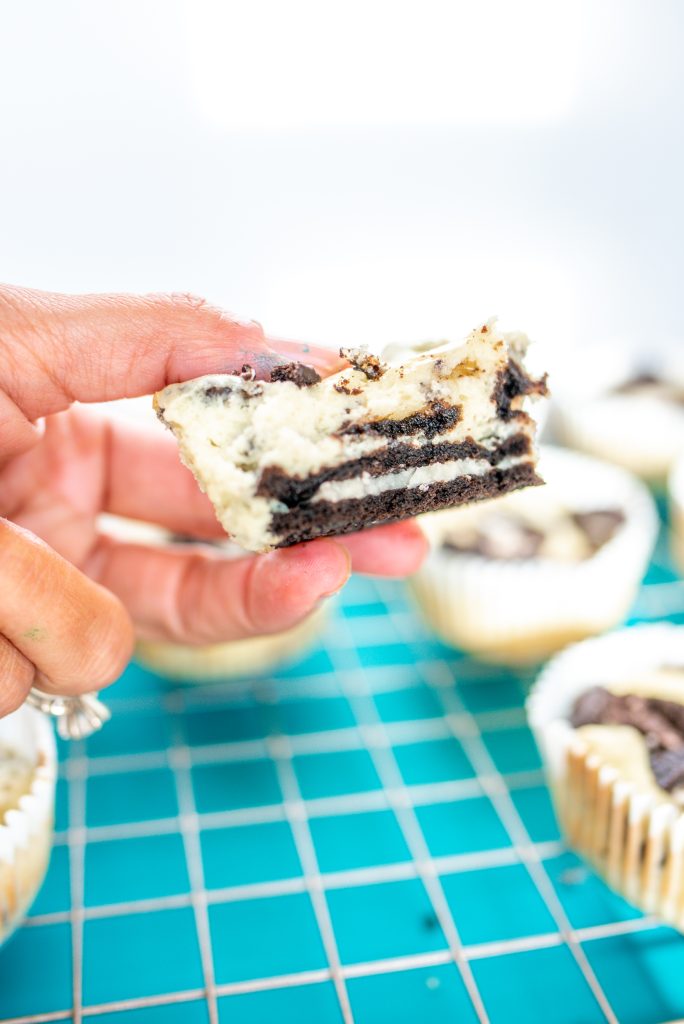 Hand holding small cheesecake bites with others in the background.