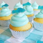 Shark cupcakes with blue frosting sitting on the table.