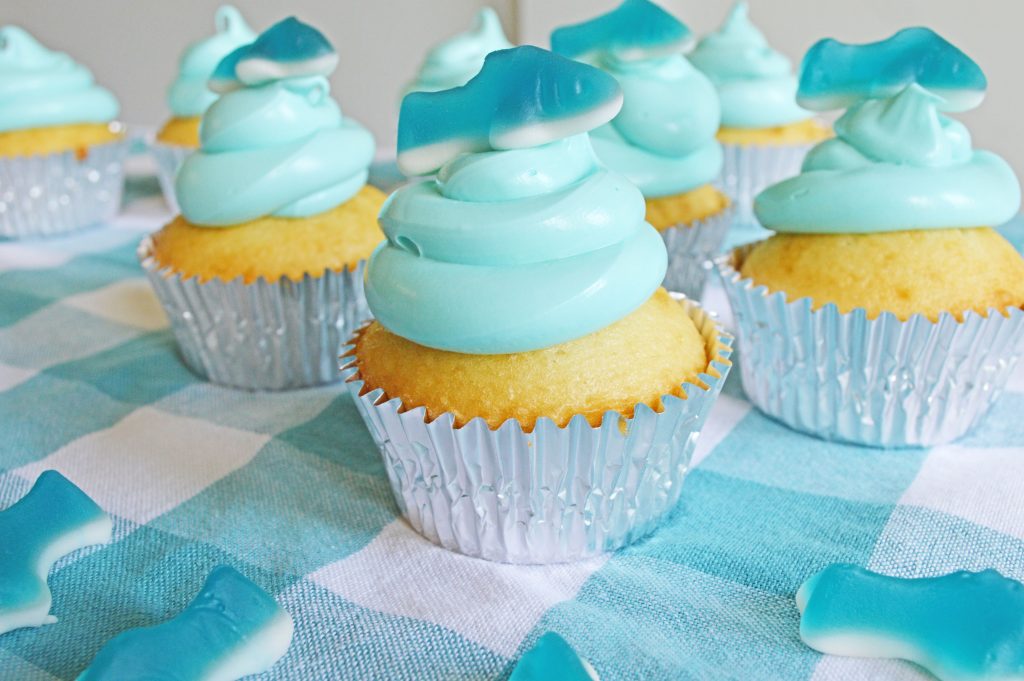 Close up of a shark cupcake with a shark gummy on top.