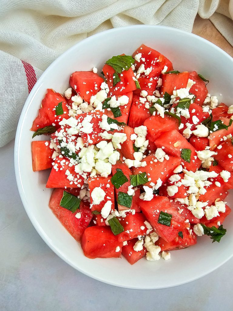 A white bowl filled with watermelon, feta, and mint salad.